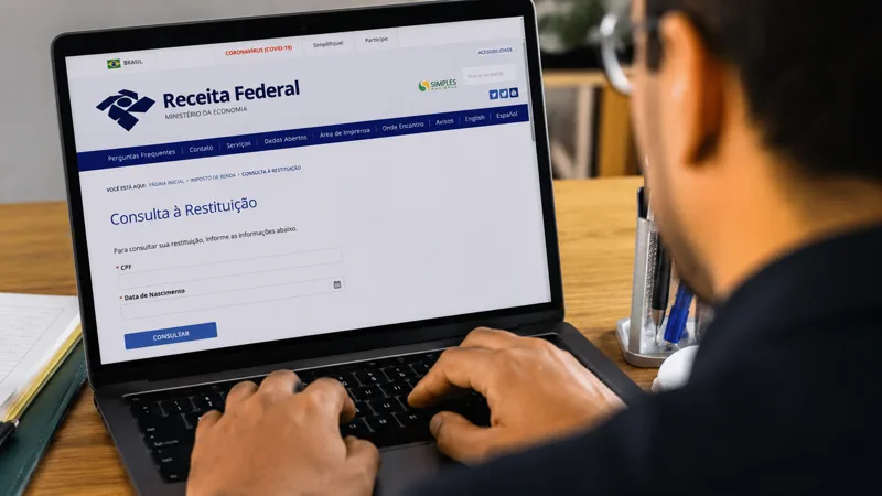 Pessoa consulta a restituição do Imposto de Renda no site da Receita Federal pelo computador.