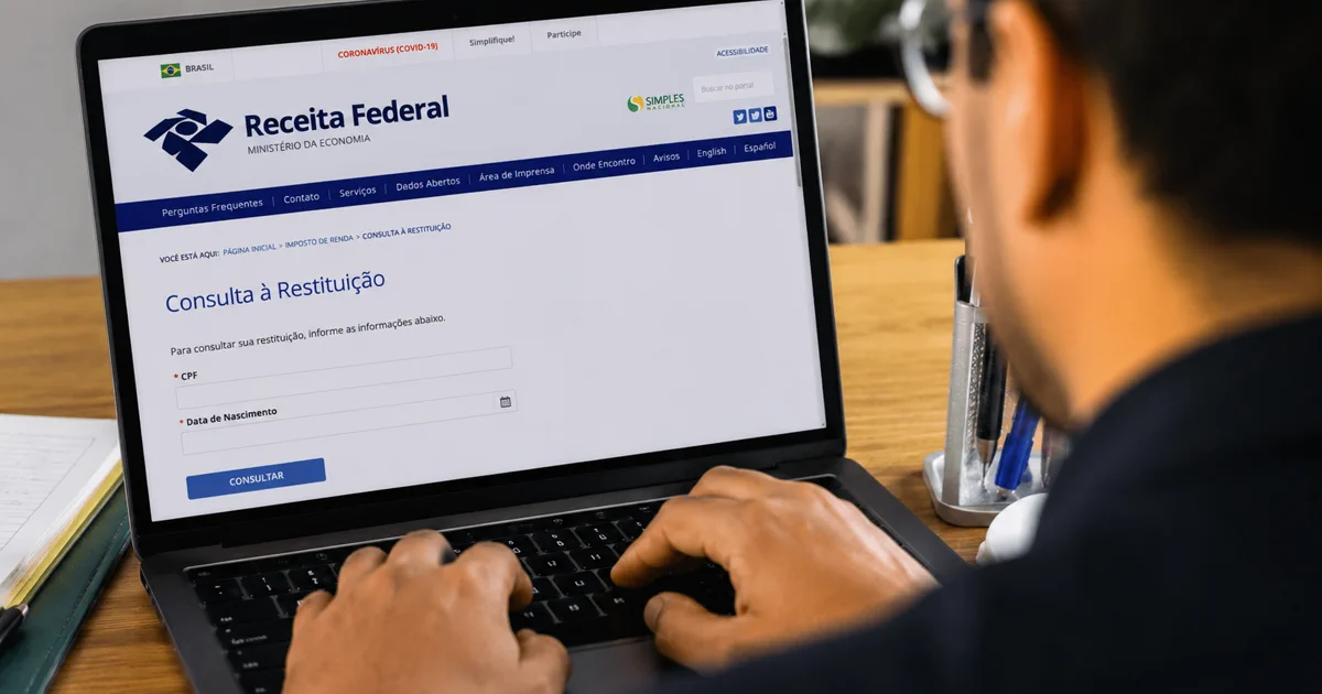 Pessoa consulta a restituição do Imposto de Renda no site da Receita Federal pelo computador.